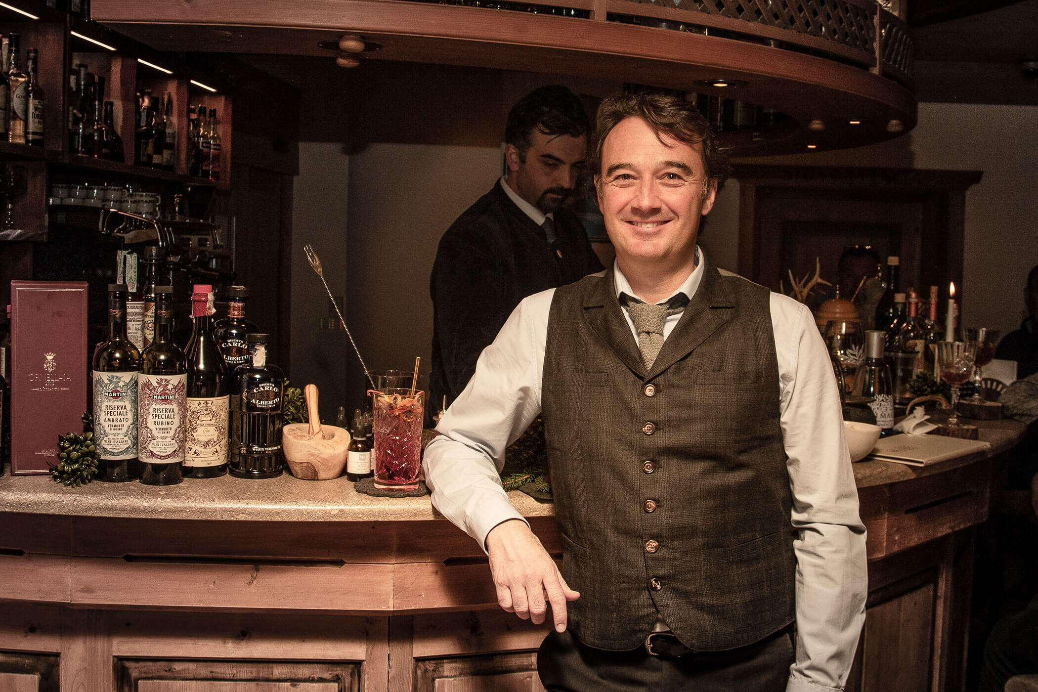 Gastgeber vor der Bar mit einem Cocktail - Posta Zirm