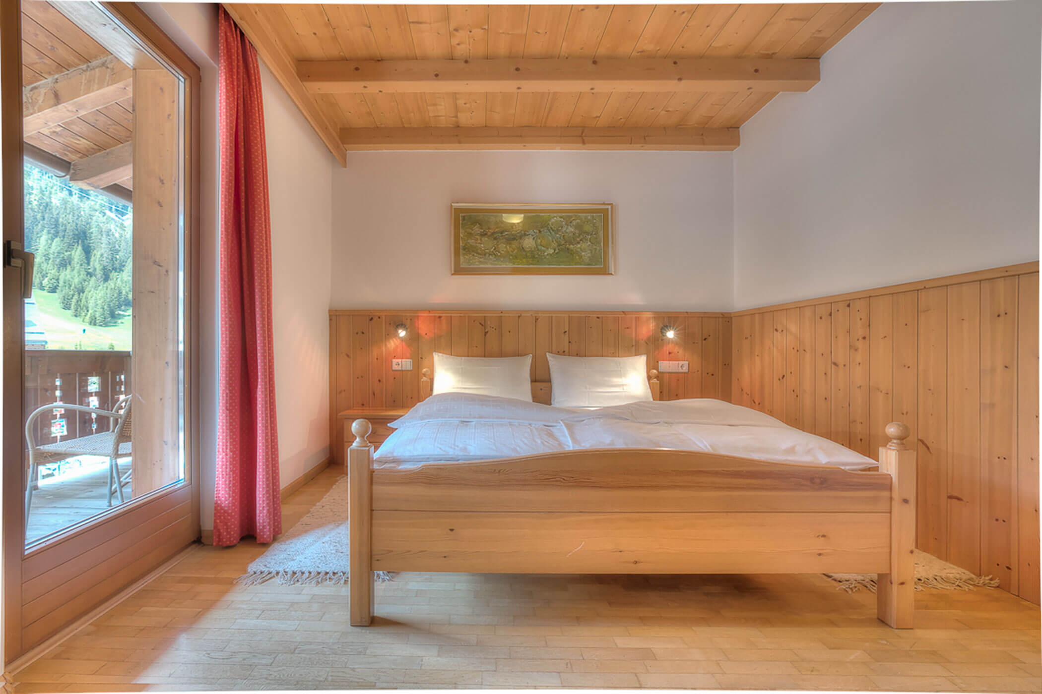 Doppelbett mit Balkontür in der Ferienwohnung Boé - Posta Zirm