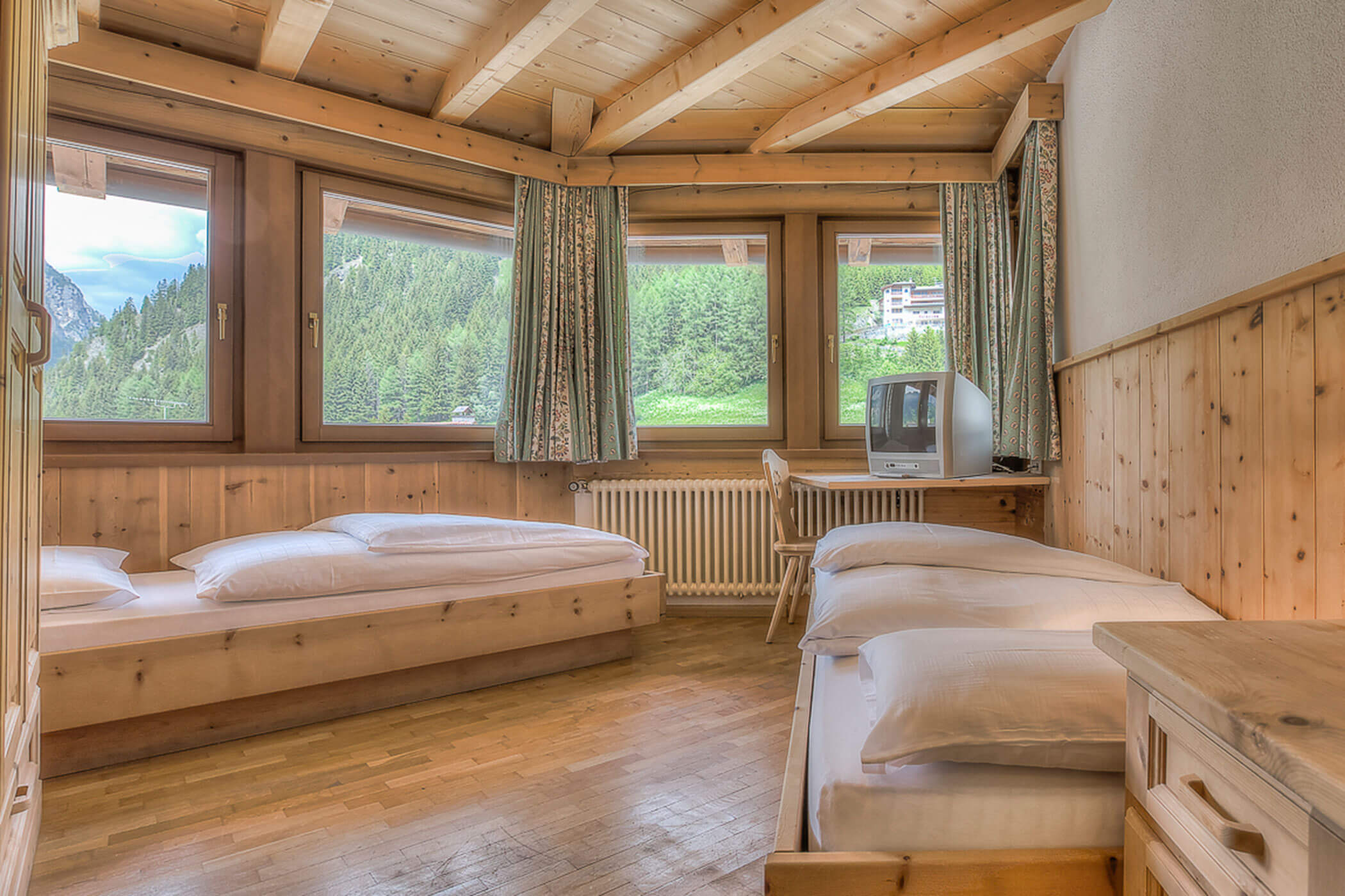 Schlafzimmer mit zwei Einzelbetten und einem TV in der Ferienwohnung Marmolada - Posta Zirm