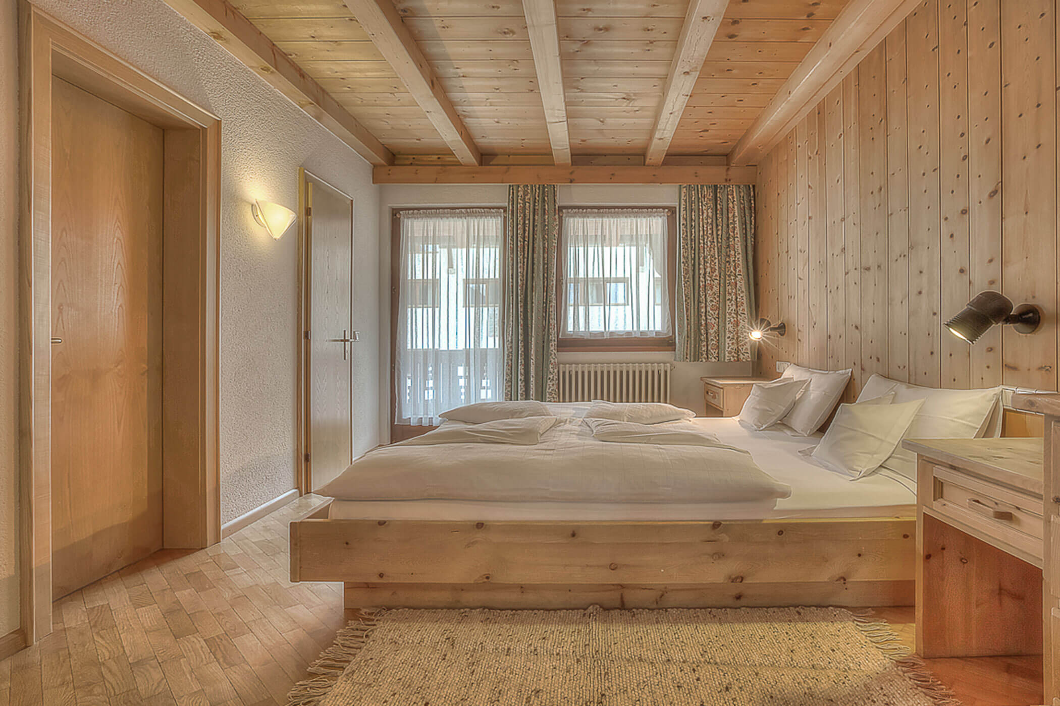 Schlafzimmer mit Doppelbett und Blick auf den Balkon in der Ferienwohnung Marmolada - Posta Zirm