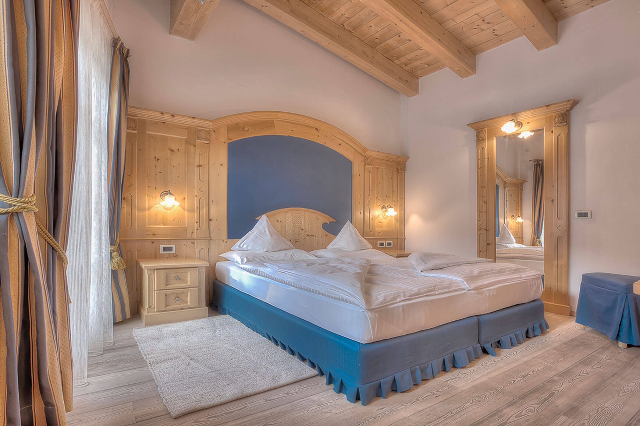 Schlafzimmer mit Doppelbett und großem Spiegel in der Ferienwohnung Rütort - Posta Zirm