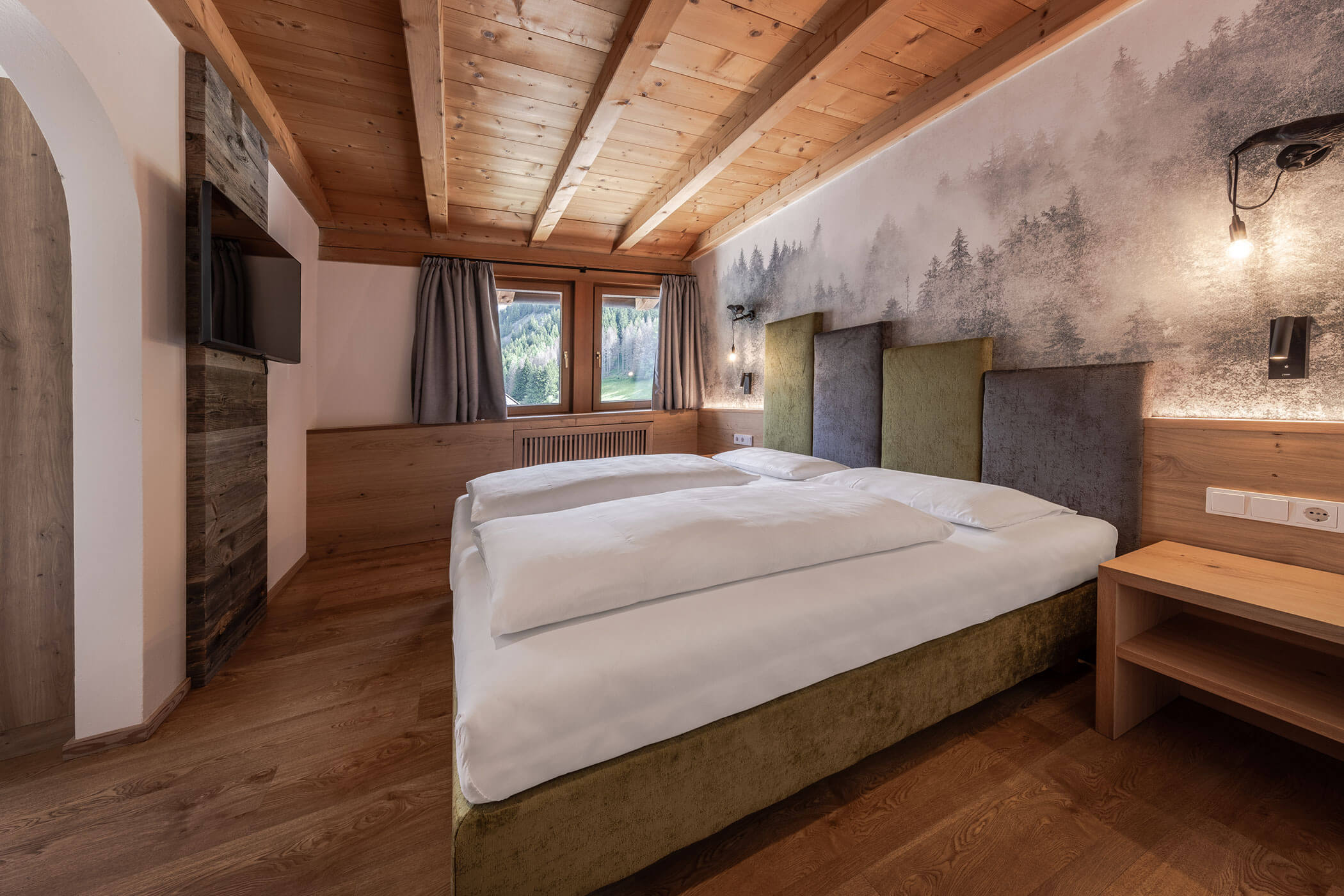 Schlafzimmer mit Doppelbett und TV in der Ferienwohnung Sassongher - Posta Zirm
