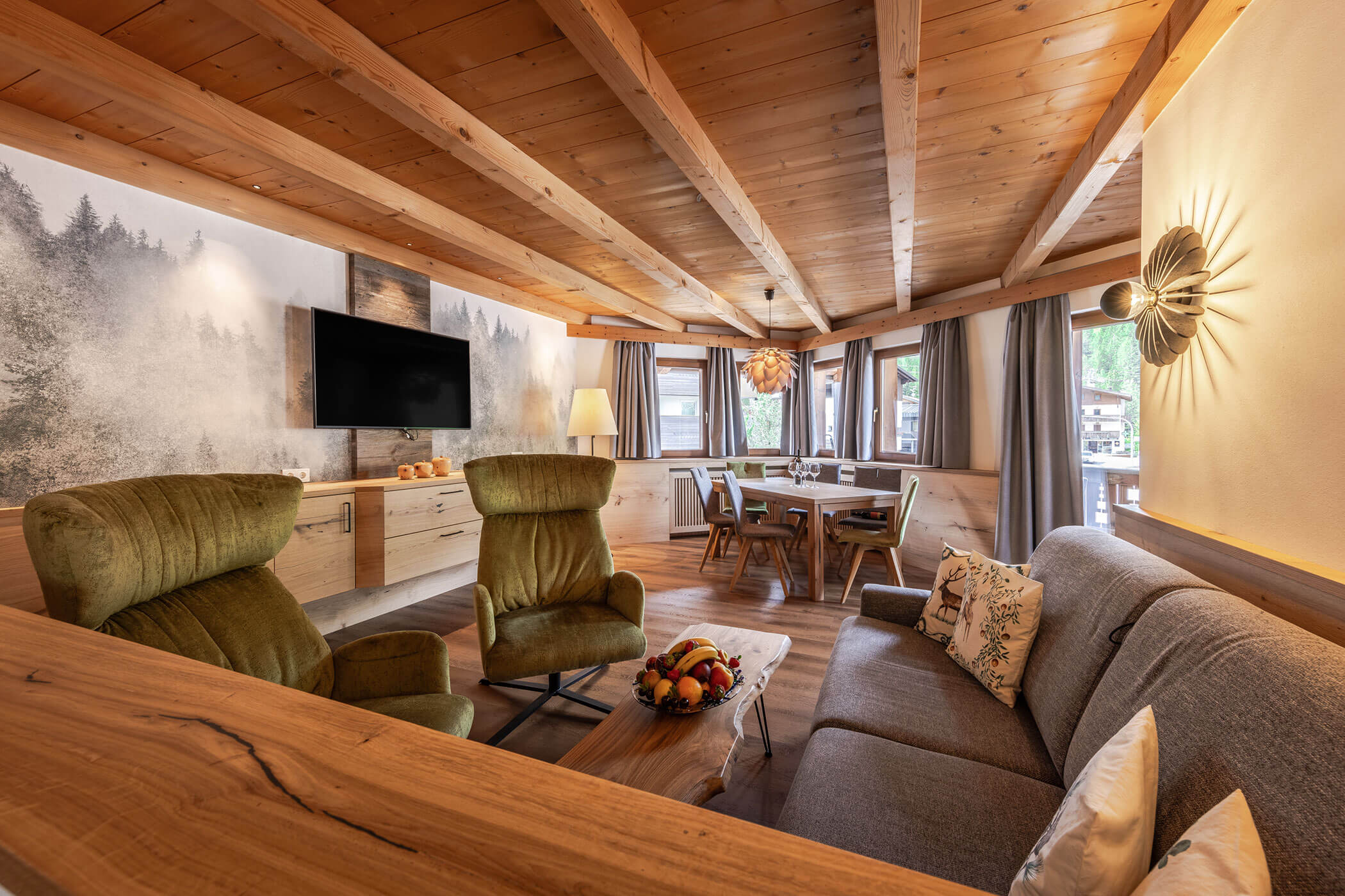 Wohnzimmer mit Sofa, Sessel und Esstisch in der Ferienwohnung Sassongher - Posta Zirm