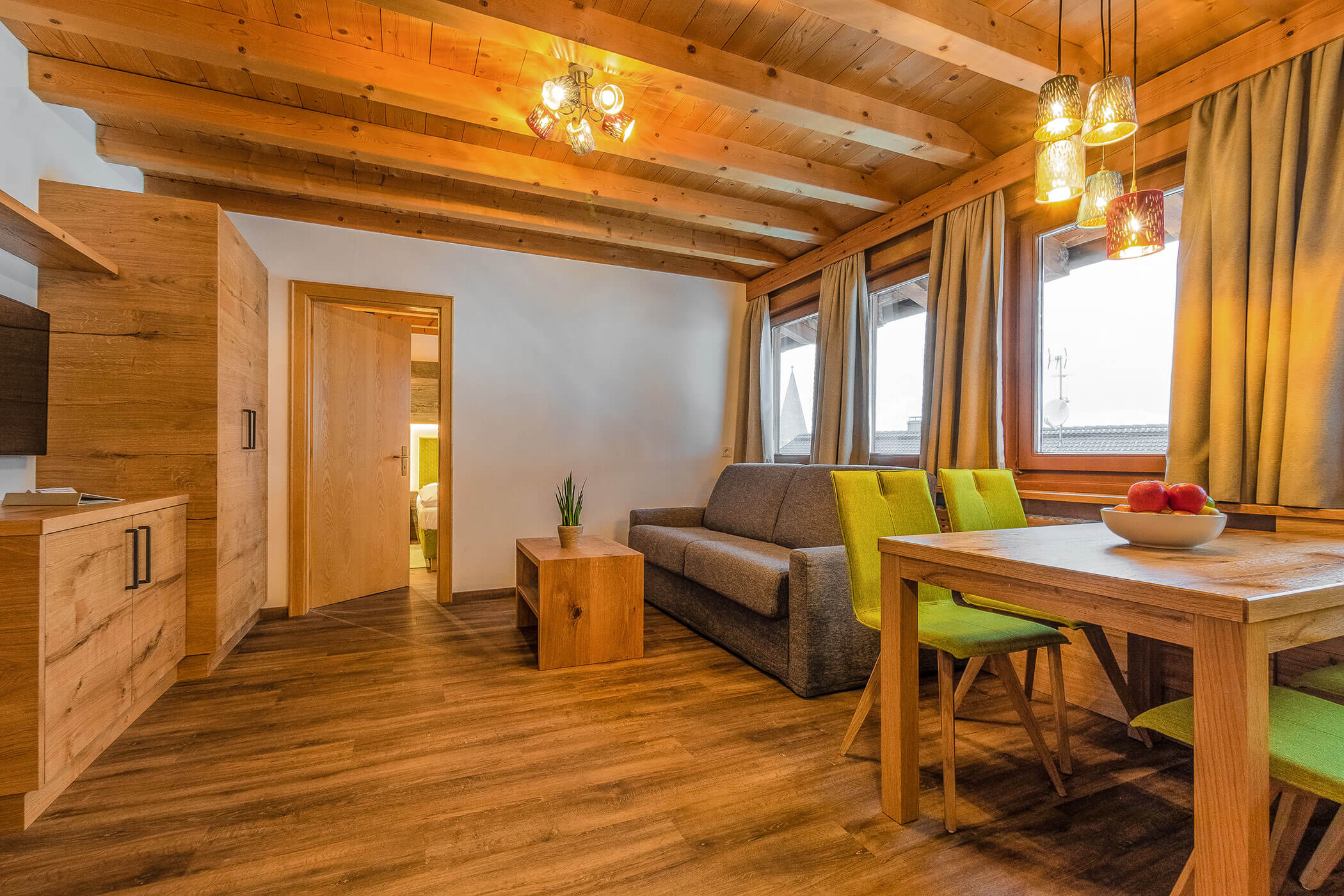 Wohnzimmer mit Sofa, TV und Esstisch in der Ferienwohnung Settsass - Posta Zirm